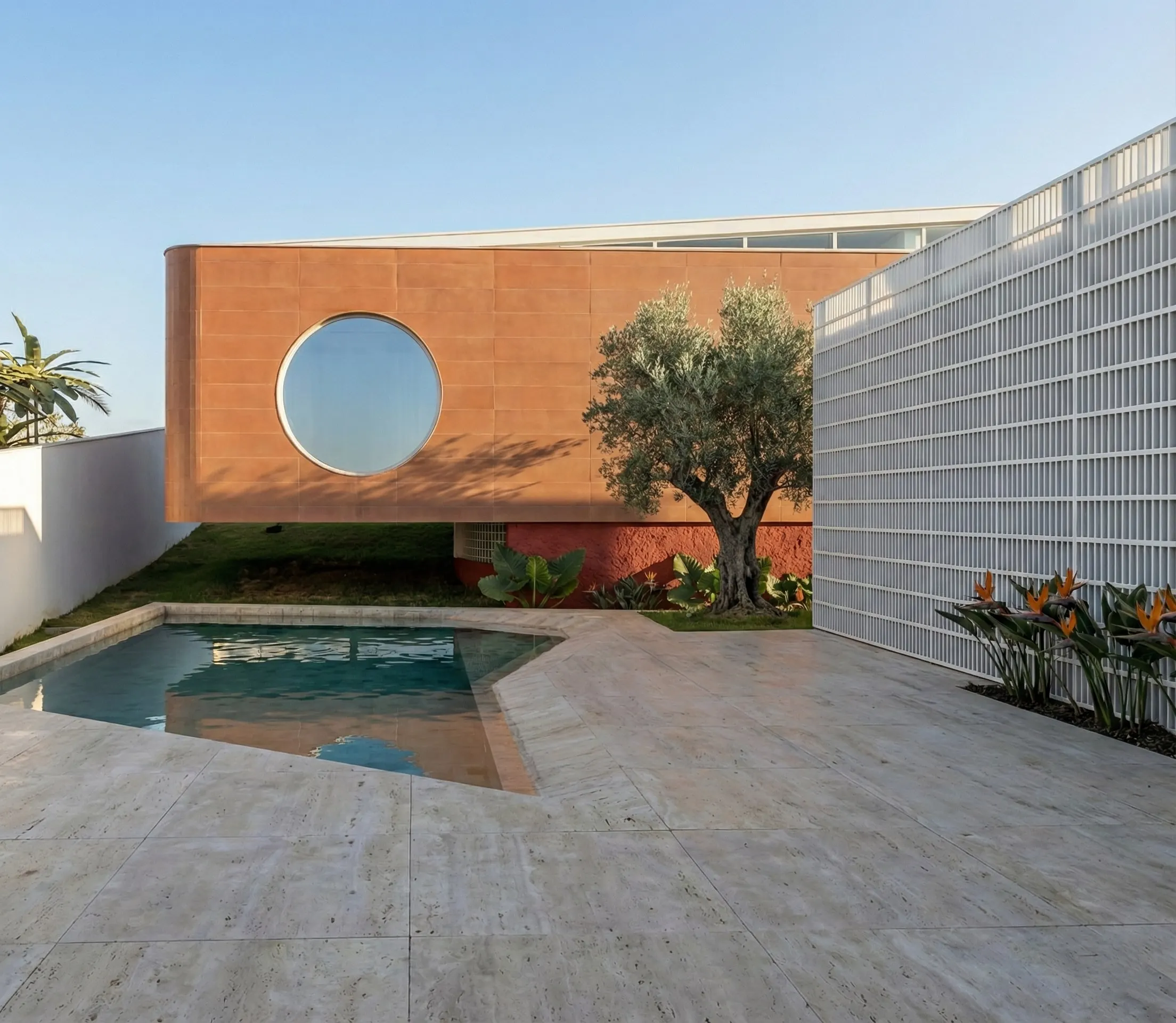 Pátio com piscina, oliveira e a janela circular no volume em terracota